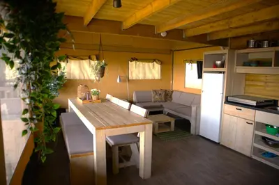 a kitchen and dining room with a table in a tiny house at Glampingtent de Saskerlei, de Woudhaven in De Woude