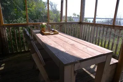 a wooden table on a porch with a plant on it at Glampingtent de Saskerlei, de Woudhaven in De Woude