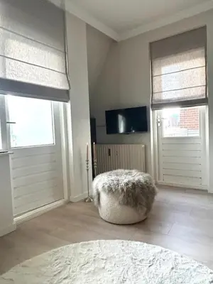 a living room with two doors and a stool at Have a nice stay! - Duinloft 150 m from the beach in Noordwijk
