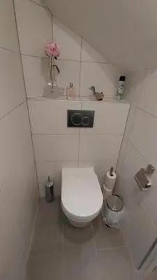 a bathroom with a toilet with a flower on a shelf at La Veranda in Zandvoort
