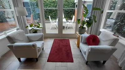 a living room with two chairs and a red rug at La Veranda in Zandvoort