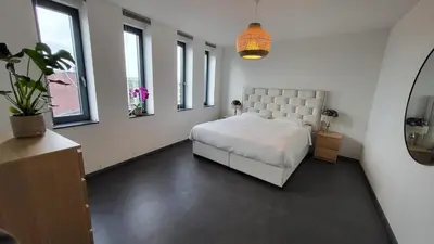 a bedroom with a large white bed and windows at B&B Kopwest 8 personen in Purmerend