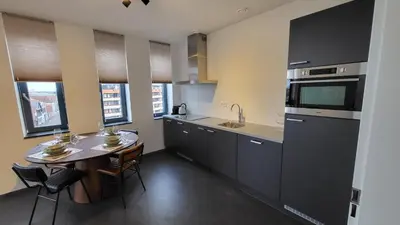 a kitchen with a table and a sink and a stove at B&B Kopwest 8 personen in Purmerend