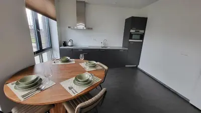 a dining room with a wooden table and a kitchen at B&B Kopwest 8 personen in Purmerend