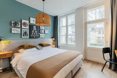 a bedroom with a bed and a desk and windows at Eye Hotel in Utrecht