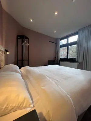 a large white bed in a bedroom with a window at Amigo Hotel in Amsterdam