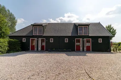 a black house with red doors and a gravel driveway at Maria's hoeve Abcoude huisje 2 dichtbij Amsterdam in Abcoude
