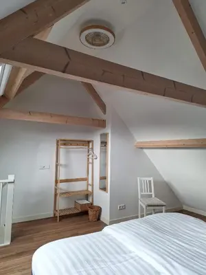 a attic bedroom with a bed and a chair at Maria's hoeve Abcoude huisje 2 dichtbij Amsterdam in Abcoude