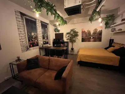 a bedroom with a bed and a couch and a desk at The Studio no windows 20 minutes by bus to downtown Amsterdam in Purmerend