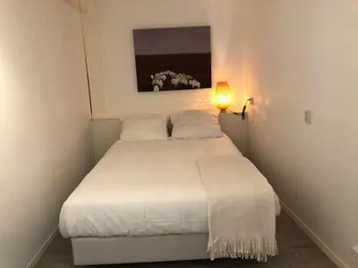 a white bed in a small bedroom with a lamp at BY BABS guesthouse Bergen nh in Bergen