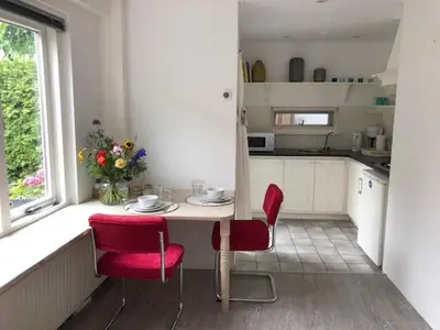 a kitchen with a table and two red chairs at BY BABS guesthouse Bergen nh in Bergen