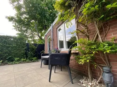 a patio with two chairs and a table and a window at BY BABS guesthouse Bergen nh in Bergen