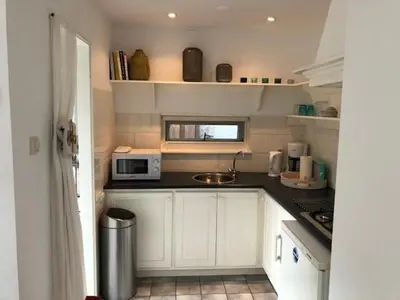 a small kitchen with white cabinets and a microwave at BY BABS guesthouse Bergen nh in Bergen