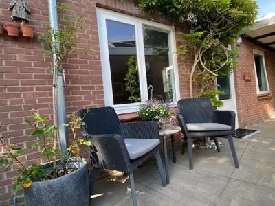 a patio with chairs and a table and a window at BY BABS guesthouse Bergen nh in Bergen