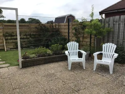 two white chairs sitting next to a fence at Chalet Goodmorning in Dirkshorn
