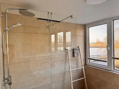a bathroom with a shower with a ladder and a window at Vakantiehuis aan meertje op Recreatiepark De Wielen - 85 in Sint Maarten