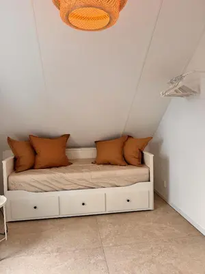 a bed with orange pillows on it in a room at Vakantiehuis aan meertje op Recreatiepark De Wielen - 85 in Sint Maarten
