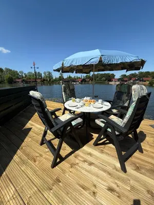 a table with chairs and an umbrella on a deck at Stillwater Lodge De Rijd in Nieuwe-Niedorp