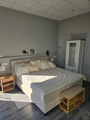 a bedroom with a large white bed with a night stand at Hart van Warder in Warder
