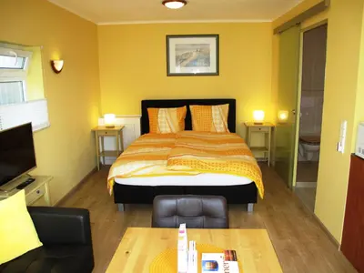 a bedroom with a bed and a couch and a tv at Duinen Paradijs Zandvoort in Zandvoort