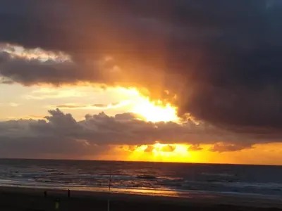 a sunset on the beach with a cloudy sky at Duinen Paradijs Zandvoort in Zandvoort