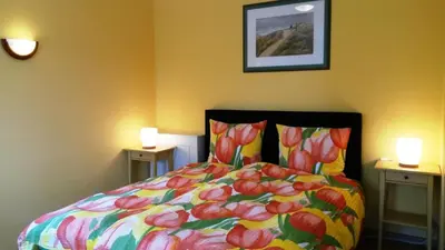 a bedroom with a bed with a colorful comforter and two lamps at Duinen Paradijs Zandvoort in Zandvoort