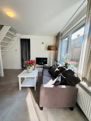 a living room with a couch and a table at Zomerhuis Aurora Noordwijk aan Zee in Noordwijk aan Zee