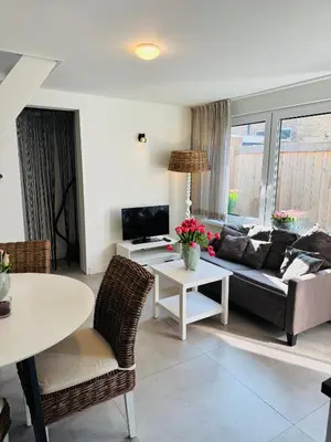 a living room with a couch and a table at Zomerhuis Aurora Noordwijk aan Zee in Noordwijk aan Zee