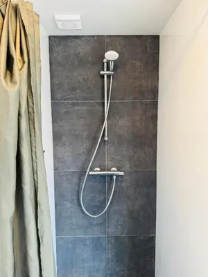a shower with a shower head in a bathroom at Zomerhuis Aurora Noordwijk aan Zee in Noordwijk aan Zee