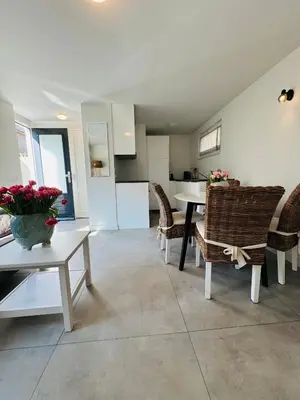 a living room with a table and chairs and a kitchen at Zomerhuis Aurora Noordwijk aan Zee in Noordwijk aan Zee