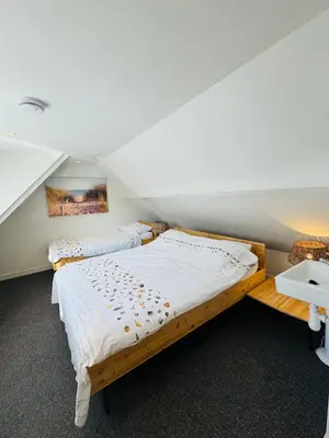 a bedroom with a wooden bed in a attic at Zomerhuis Aurora Noordwijk aan Zee in Noordwijk aan Zee