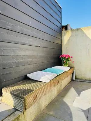 a wooden bench sitting on the side of a building at Zomerhuis Aurora Noordwijk aan Zee in Noordwijk aan Zee