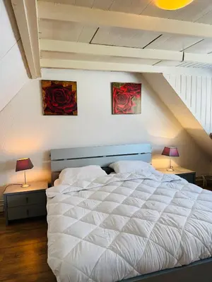 a bedroom with a large white bed with two lamps at Strandhuisje Quarles in Noordwijk