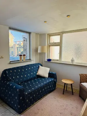a living room with a blue couch and windows at Strandhuisje Quarles in Noordwijk