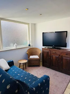 a living room with a couch and a flat screen tv at Strandhuisje Quarles in Noordwijk