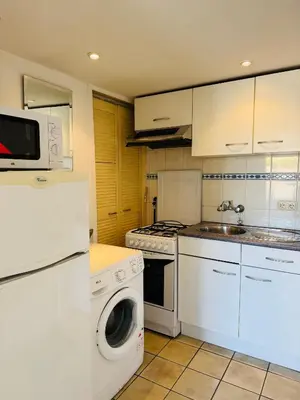 a kitchen with white appliances and a washer and dryer at Strandhuisje Quarles in Noordwijk