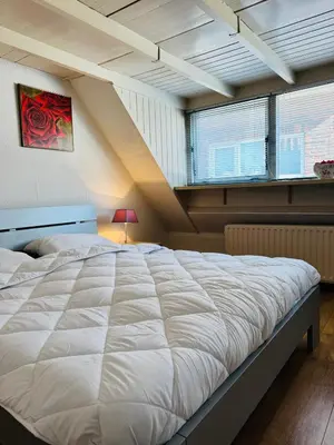 a large white bed in a room with windows at Strandhuisje Quarles in Noordwijk