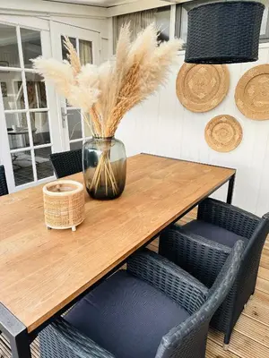 a wooden table with chairs and a vase with feathers at Beleef Noordwijk strandhuisje in Noordwijk aan Zee