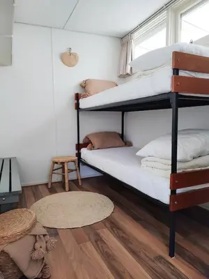 two bunk beds in a room with a wooden floor at Beleef Noordwijk strandhuisje in Noordwijk aan Zee