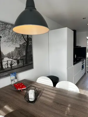 a dining room with a table and a black light fixture at De Schelp 67, Free parking in Zandvoort