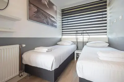 two twin beds in a room with a window at De Schelp 67, Free parking in Zandvoort