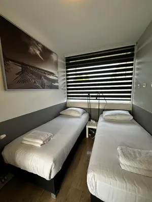 two twin beds in a room with a window at De Schelp 67, Free parking in Zandvoort