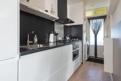 a kitchen with white cabinets and a sink at De Schelp 67, Free parking in Zandvoort