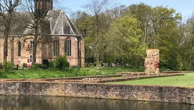 an old building with a clock tower next to a body of water at Slotje in Egmond aan den Hoef