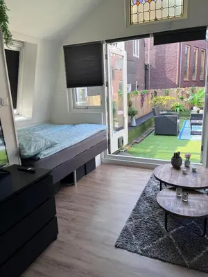 a bedroom with a bed and a view of a yard at Comfortabel studio 19 min from downtown Amsterdam in Purmerend