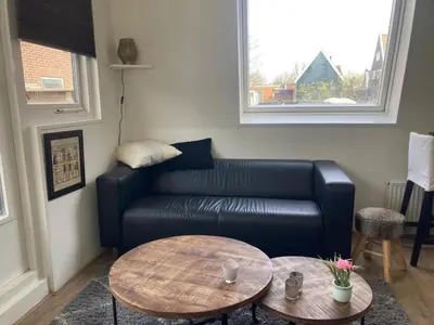 a living room with a leather couch and a table at Comfortabel studio 19 min from downtown Amsterdam in Purmerend
