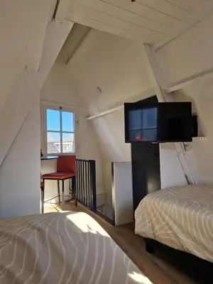 a bedroom with a bed and a flat screen tv at Bed & Breakfast De Punt in Monnickendam