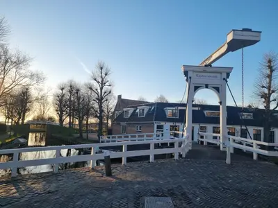 a white fence next to a building with a crane at Bed & Breakfast De Punt in Monnickendam