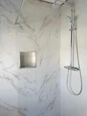 a shower in a bathroom with white marble walls at Blom studio's in Hillegom