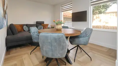 a living room with a table and chairs and a couch at Steenhof Beach House in Noordwijk